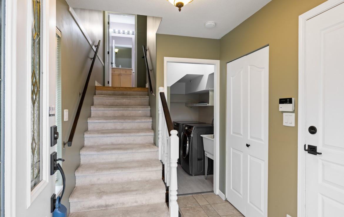 View from the front door leading to the laundry room, staircase to a bathroom and closets.