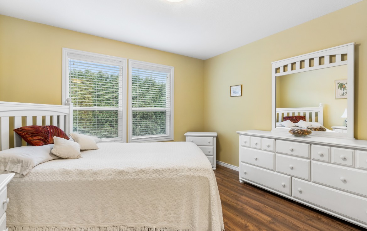 Large primary bedroom with bed, dresser and end tables.